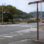 街道が国道34号線をまたぐ。向こうに「日見腹切坂の石碑」がみえる(宿町)