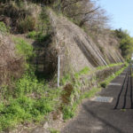 国道34号線の歩道。見えないが左側にボートレースの看板。その辺りに旧街道が通っていたと推測。よく見ると階段があり、上に行けるようにはなっている。(東彼杵町里郷622付近)