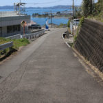 街道、上り坂を(小倉方面へ)振り返る。奥に日本二十六聖人の乗船場跡が見える(彼杵宿郷1085付近)