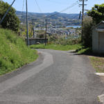 街道の下り坂。奥に山と海と街並みがみえる(千綿宿郷68付近)