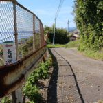 フェンス越しの街道(小倉方面むき)。左(南東)に国道と線路と海。(瀬戸郷1331付近)